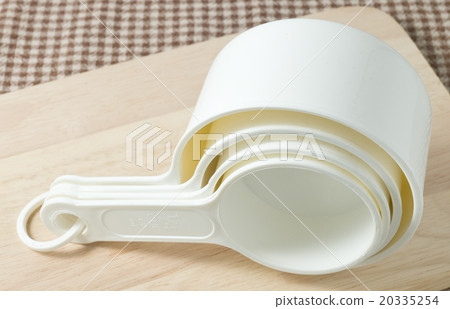 Four White Plastic Measuring Cups on Wooden Board 20335254