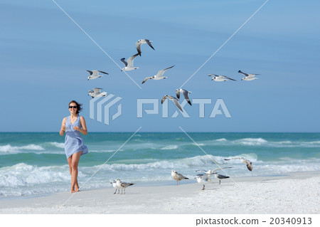 Young woman feeding seagulls on tropical beach 20340913