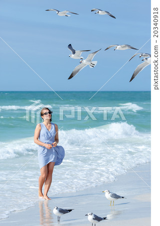 Young woman feeding seagulls on tropical beach 20340918