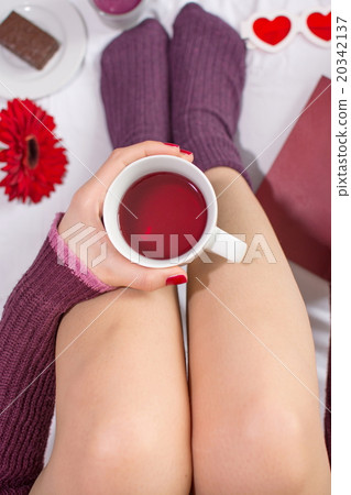 Woman having a cup of tea in bed Woman having a cup of tea in bed 20342137