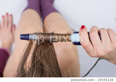 Girl straightening her hair in bed Girl straightening her hair in bed 20342138