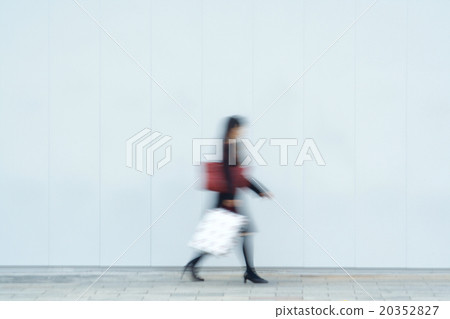 Woman walking in front of white wall motion blur 20352827