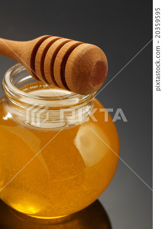 glass jar of honey and stick on black 20359595