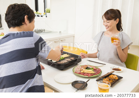 A young couple who roasts grilled meat on a hot plate A young couple who roasts grilled meat on a hot plate 20377733