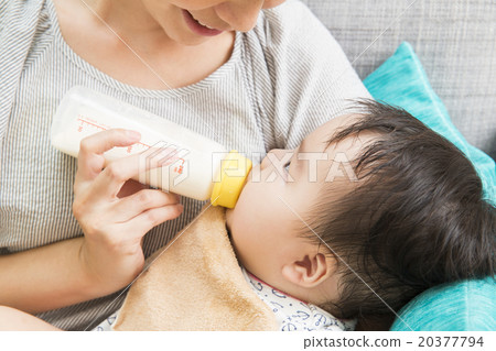 A young mother who makes a baby drink milk 20377794
