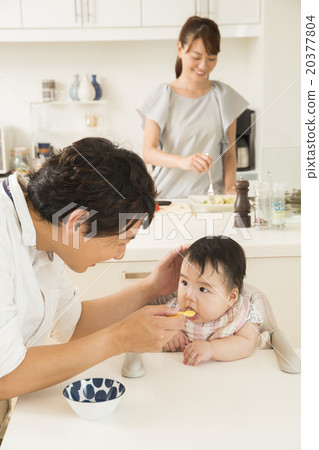 Dad raising baby food to baby 20377804