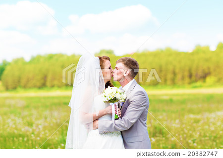 Beautiful wedding couple in park. They kiss and Beautiful wedding couple in park. They kiss and 20382747