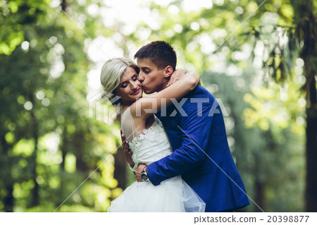 Beautiful wedding couple hugging in the park Beautiful wedding couple hugging in the park 20398877