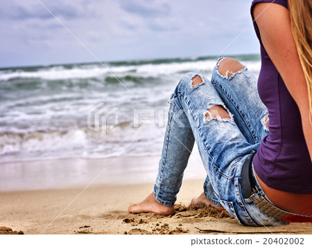 Legs of woman sitting on coast near ocean with Legs of woman sitting on coast near ocean with 20402002