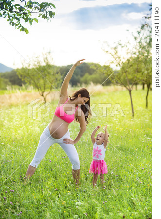 Pregnant mother with her daughter exercising 20411190