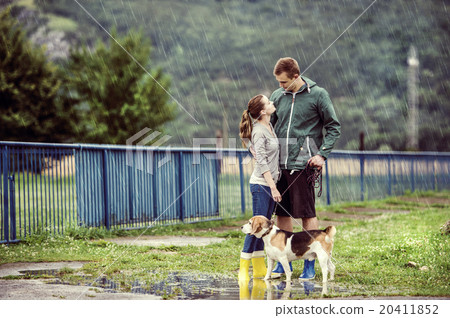 Young couple walk dog in rain Young couple walk dog in rain 20411852