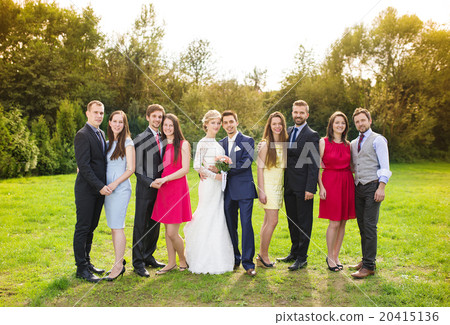 Newlyweds with guest posing in park 20415136