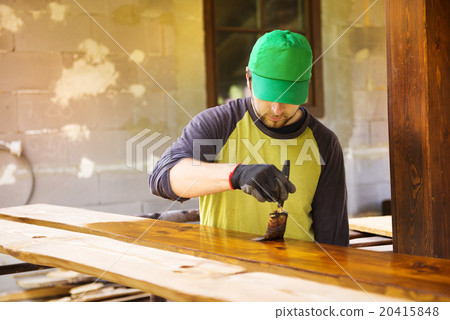 Handyman varnishing wooden planks outside 20415848