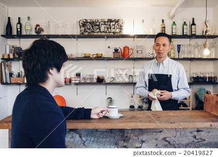 A man who talks with an owner at a cafe 20419827