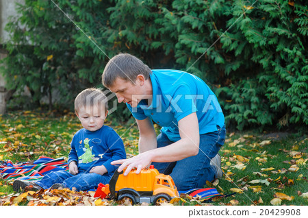 Father and son playing in the park toy car in a park on the gras Father and son playing in the park toy car in a park on the gras 20429908