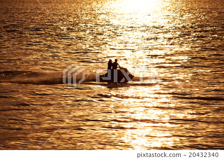 Silhouette of people on jet-ski against the sunset 20432340