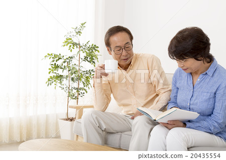 Senior couple reading relaxing in the living room Senior couple reading relaxing in the living room 20435554