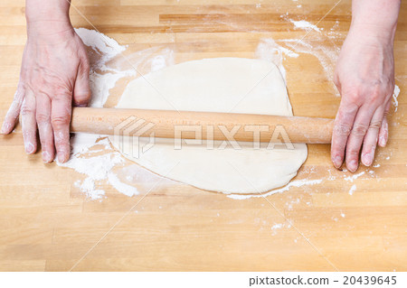 female hands roll out dough with rolling pin 20439645