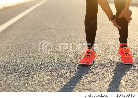 woman runner hold her injured leg on road 20439919