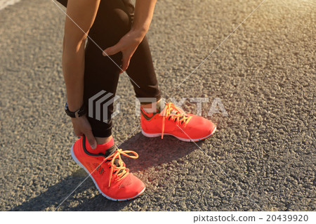 woman runner hold her injured leg on road. 20439920