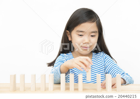 使用在多米諾構建塊的女孩演奏小學女孩多米諾構件 20440215