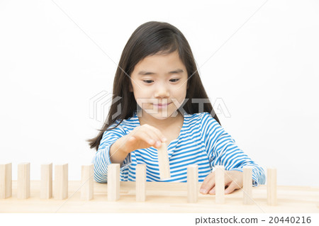 使用在多米諾構建塊的女孩演奏小學女孩多米諾構件 20440216