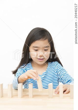 使用在多米諾構建塊的女孩演奏小學女孩多米諾構件 20440217