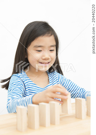 使用在多米諾構建塊的女孩演奏小學女孩多米諾構件 20440220