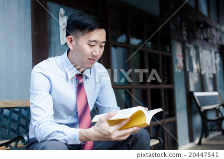 Asian Man Reading a Book Sitting on Bench 20447541