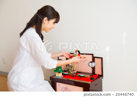 A woman decorating a doll doll (mother) 20448740