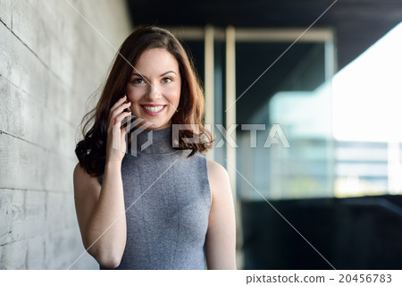 Businesswoman talking with a smartphone in an office building 20456783
