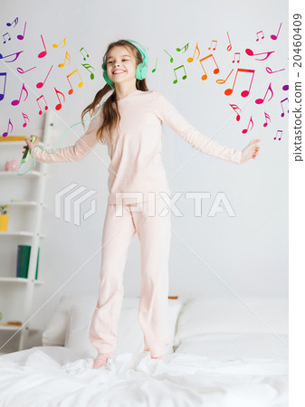 girl jumping on bed with smartphone and headphones 20460409