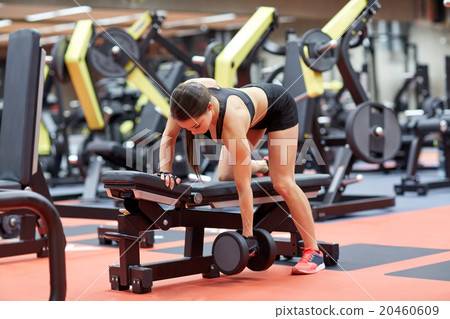 young woman flexing muscles with dumbbell in gym young woman flexing muscles with dumbbell in gym 20460609