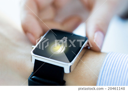 close up of hands with lightbulb on smartwatch close up of hands with lightbulb on smartwatch 20461148