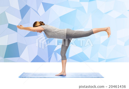 woman making yoga warrior pose on mat 20461436