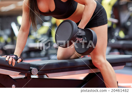 woman flexing muscles with dumbbell in gym 20461482