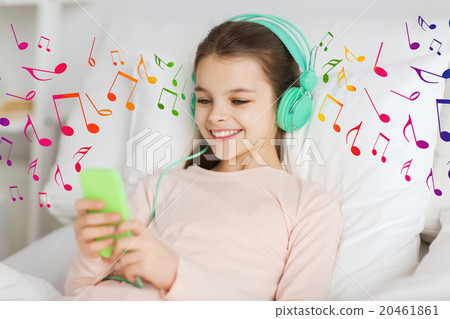 happy girl in bed with smartphone and headphones 20461861