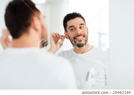 man cleaning ear with cotton swab at bathroom man cleaning ear with cotton swab at bathroom 20462184