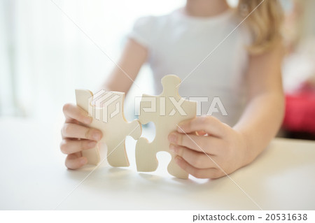 Child girl holding two big wooden puzzle pieces Child girl holding two big wooden puzzle pieces 20531638