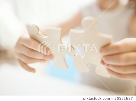 Child girl holding two big wooden puzzle pieces Child girl holding two big wooden puzzle pieces 20531657