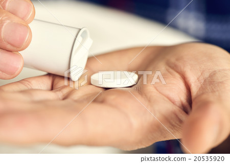 man in bed about to take a tablet 20535920