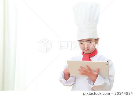 A 6 year old little chef watching the tablet A 6 year old little chef watching the tablet 20544854