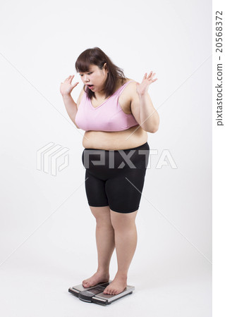 一個胖的年輕女士，驚訝地在白色背景前的規模上 20568372