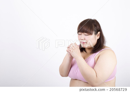 A fat young woman praying closing her eyes in front of a white background 20568729