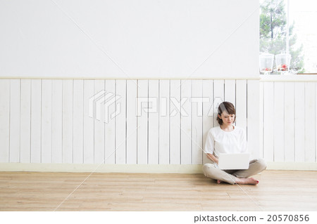 A young woman sitting on the floor and operating a computer A young woman sitting on the floor and operating a computer 20570856
