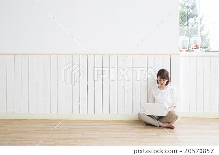 A young woman sitting on the floor and operating a computer 20570857