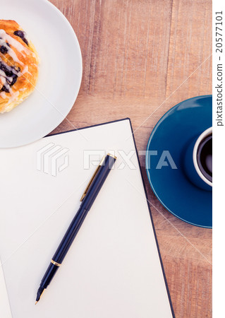 Pen on notepad by food and coffee at table 20577101