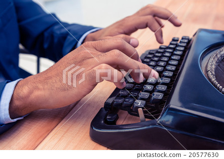 Businessman using typewriter at wooden desk 20577630