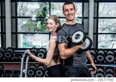 Fit couple lifting dumbbells back to back Fit couple lifting dumbbells back to back 20577700