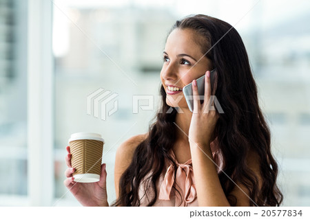 Smiling woman on phone call holding disposable cup Smiling woman on phone call holding disposable cup 20577834